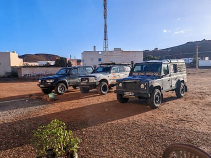 Drei Geländewagen auf rotem Sand, bereit für die Piste