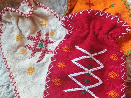 Drei handgewebte Wärmeflaschenhüllen in Rot, Orange und Naturweiß