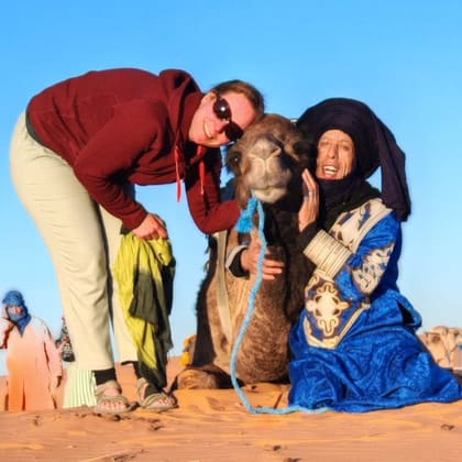 Isabelle und Ali mit einem Kamel in den Dünen